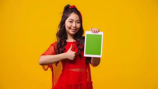 Satisfeito asiático mulher segurando digital tablet com verde tela e mostrando como isolado no amarelo — Fotografia de Stock