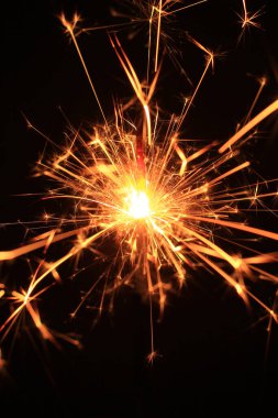 Noel ve Yeni Yıl partisi maytapları siyah arka planda, neşeli kıvılcım efektleriyle parıldıyor, ince film tahılları, sıcak altın tonları, bokeh ışıkları, klasik atmosfer ekleme sesi.