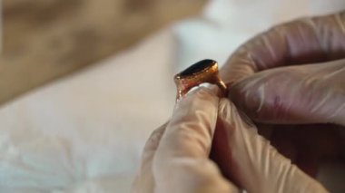 Zanaatkar bakır küpeler ve mücevherler yapar. Yeni yapılmış bir mücevher yüzüğünü temizlerken ellerinizi kapatın. El yapımı çalışmalar atölyesi. Hobiler ve eski profesyonel tutkular. İş bitti..