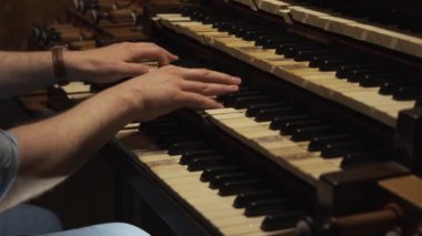 Uzman bir orgcu büyük bir kilise org klavyesi çalar. Kutsal müzik eşliğinde eller hızlı hareket eder. Müzisyen tuşlara basar ve sesi durdurma ve çubuklarla ayarlar ve ayrıca ayak pedalları kullanır.