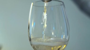 Şampanyanın bardağa doldurulduğu yakın plan. Parti sırasında bir kadehe köpüklü beyaz şarap döküldü. 4k ağır çekim videosu.