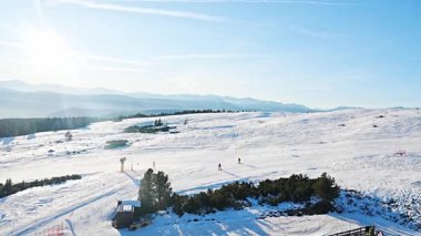 Vadiden inen iki kayakçının hava görüntüleri. Amatör kayakçılar öğleden sonra soğuk karda tek başlarına kayak yaparlar. Kış sporları, insanlar kayak yokuşundan aşağı inerler. Teleferiğin hareket videosu..