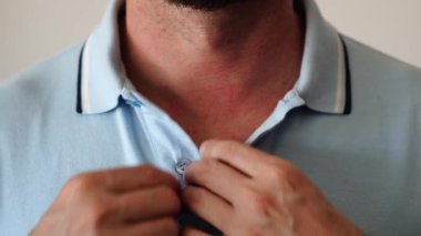 Polo tişörtünü ilikleyen eller tam olarak değil. Renkli bir polonun yakasını nasıl ilikleyeceğinin yakın çekimi. Poloshirt yakasını düzelten adam üst düğmeyi açıyor. Rahat ve resmi giyinmiş hissediyorum..