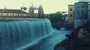 Endüstriyel şehir merkezinde büyük bir şelale. Motala Strm nehri gün batımında İsveç şehri boyunca akar. İnşaat mühendisliği ve mimarlık sanatı.