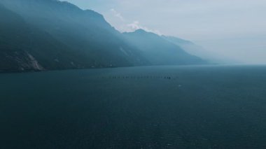 Tekneler ve yelkenli gemileri gölün ortasında toplanıyor. Garda Gölü 'nde hava görüntüsü. Yaz sporları, yelkencilik yarışı, hazırlıklar. Özgürlük, sessizlik, barış, deniz sporları. 4k stok görüntüsü.