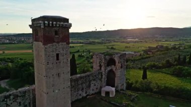 Montorio Veronese Kalesi, Verona. Gün batımında büyük bir ortaçağ şatosunun hava görüntüsü. Kırsal bölgede duvarlar ve yüksek kule var. 4k, 50 fp.