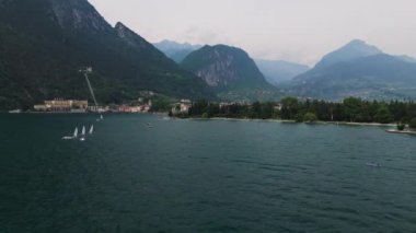 Riva del Garda 'nın hava görüntüsü. Garda Gölü 'nün ünlü limanı. Büyük İtalyan gölünün yüzeyinde yelken açan tekneleri var. Barış, yaz aktiviteleri, mavi sular ve dağlar. Stok görüntüsü 4k 50fps.