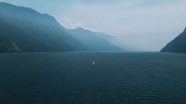 Tekneler ve yelkenli gemileri gölün ortasında toplanıyor. Garda Gölü 'nde hava görüntüsü. Yaz sporları, yelkencilik yarışı, hazırlıklar. Özgürlük, sessizlik, barış, deniz sporları. 4k stok görüntüsü.