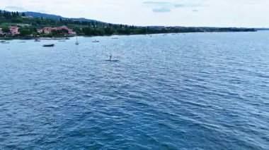 Adam su üzerinde hidrofolyo sörf tahtasıyla uçuyor. Uzak mesafedeki sporcu gün batımında büyük bir gölde folyo sörf tahtasına biner. İnsan ve su, havadan 4k atış, doğayla temas, ekstrem sporlar, özgürlük.