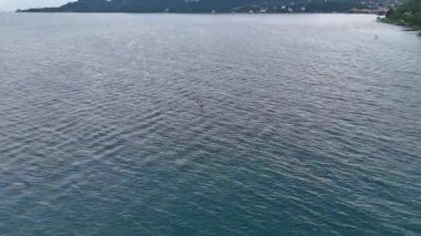 Adam su üzerinde hidrofolyo sörf tahtasıyla uçuyor. Uzak mesafedeki sporcu gün batımında büyük bir gölde folyo sörf tahtasına biner. İnsan ve su, havadan 4k atış, doğayla temas, ekstrem sporlar, özgürlük.