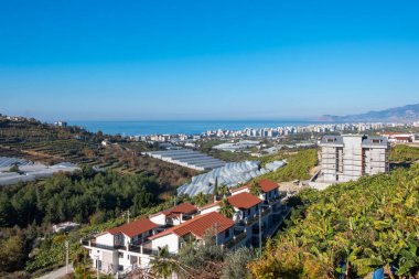 Alanya, Türkiye - 4 Ocak 2023. Akdeniz ve dağların çarpıcı manzaralı apartman kompleksleri sabah güneşinin altında..
