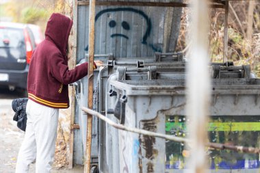 Evsiz biri Ukrayna 'da yiyecek aramak için çöp tenekesine eğildi..