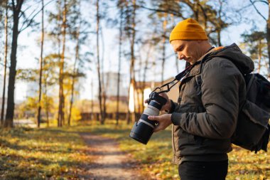 Genç fotoğrafçı ormanda fotoğraf çekiyor. Büyük profesyonel kameralı fotoğrafçı..