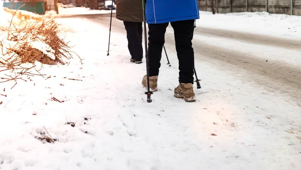 Winter sport in Finland is Nordic walking. Man and senior woman hiking in cold forest. Active people outdoors.