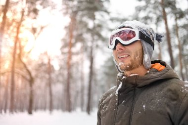 Soğuk bir günde, karlı bir ormanda derin derin nefes alan sakallı mutlu bir adam..