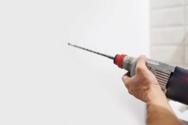 Drilling a white wall with a drill close-up.