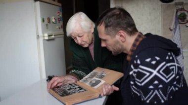 Büyükannem ve torunum birlikte bir fotoğraf albümüne bakıyorlar. Büyükanne torununa geçmişten anılar gösteriyor..