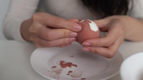 女性の手は暗い木製の背景にゆで卵の殻をきれいにします 調理の準備 — ストック動画