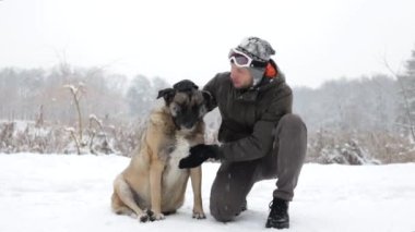 Kışın köpekli genç bir adam. Yaşlı köpeğiyle kış ormanında yürüyen bir hayvan sahibi..