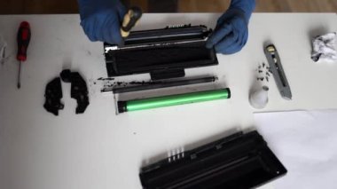 Yazıcı kartuşu tamiri. Hizmet merkezi ve atölye konsepti. Yazıcı için şarjör dolduran adam. Mürekkep şişesi beyaz masada. Tamirci eldivenle tamir ediyor..