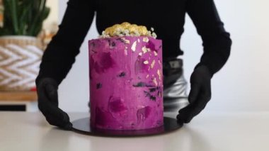 Yemek pişirmek ve altın pullu pasta süslemek. Genç kadın pasta şefi pembe pasta süslüyor. Mutfakta siyah eldivenli mutlu kadın güzel doğum günü pastası, aşçılık ve pasta becerileri yapıyor..