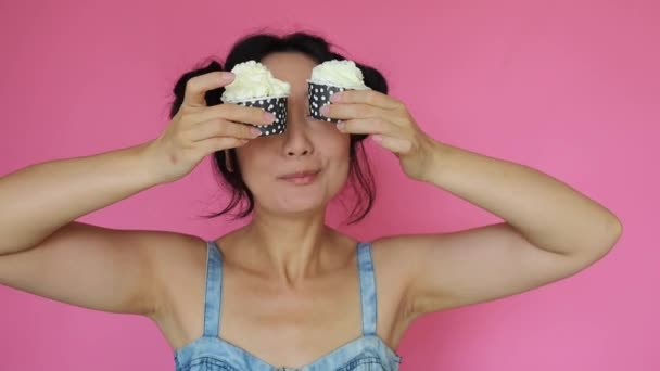 Schattig Aziatisch Meisje Houdt Een Cupcake Met Room Roze Achtergrond — Stockvideo