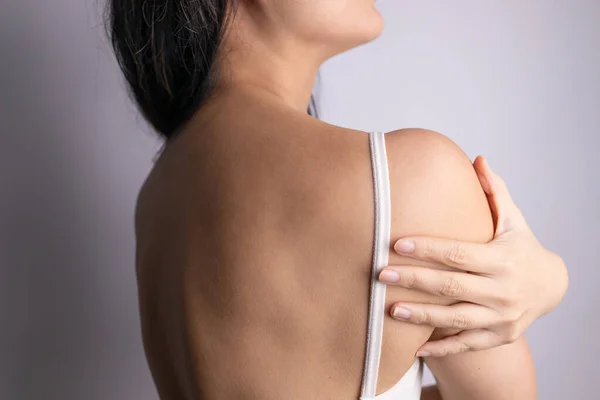 Closeup shot of woman from back having neck or shoulder pain. Injury or muscle spasm. Back and spine disease. Female massaging her neck. Health care and medical concept.