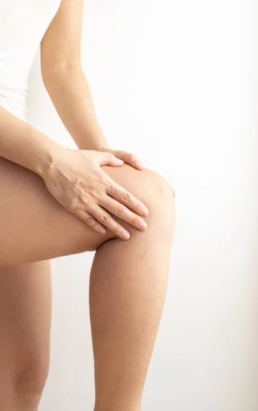 Joint pain, arthritis and tendon problems. Woman touching her knee at a painful point, on a white background