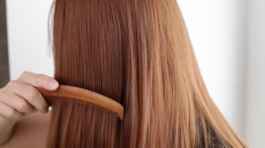 Closeup on a young woman combing her hair