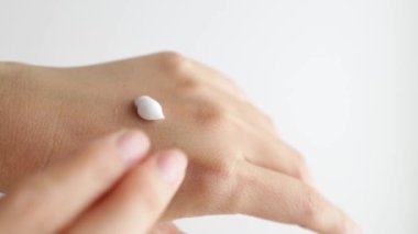 Female hands care. Close up shot of asian lady applying cream on hand skin, slow motion