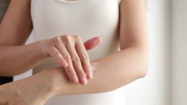 Female hands care. Close up shot of asian lady applying cream on hand skin, slow motion