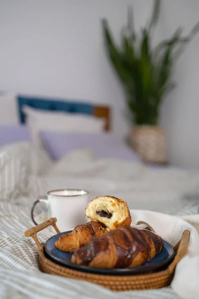 breakfast, cozy, morning, holidays and winter concept - cozy bedroom with cup of coffee and croissant on wooden board in bed at home