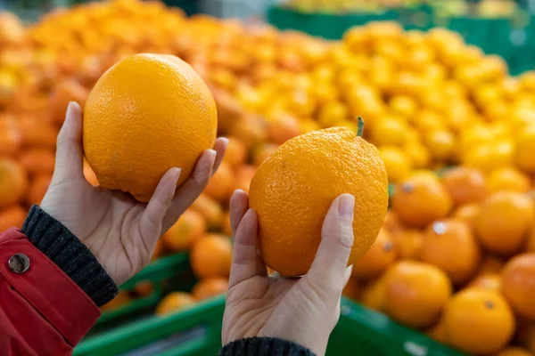 woman\'s hand choosing orange from the food counter at the supermarket.