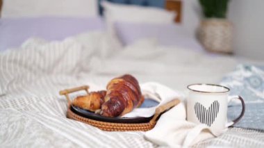 breakfast, cozy, morning, holidays and winter concept - cozy bedroom with cup of coffee and croissant on wooden board in bed at home