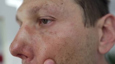 close up video how a man is applying a man massaging coffee scrub on his face. man is doing at home skin routine. body and face care. beauty concept. spa and wellness.