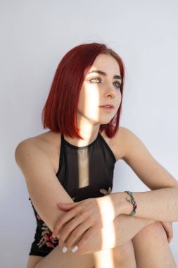 Glamorous portrait of a beautiful woman model with fresh daily makeup and short red hair. Fashion glitter highlighter on skin, sexy lip gloss makeup and dark eyebrows