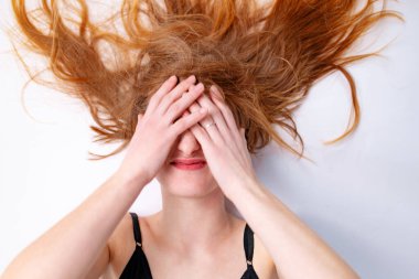 Beautiful woman with long crazy red hair and eyes closed.