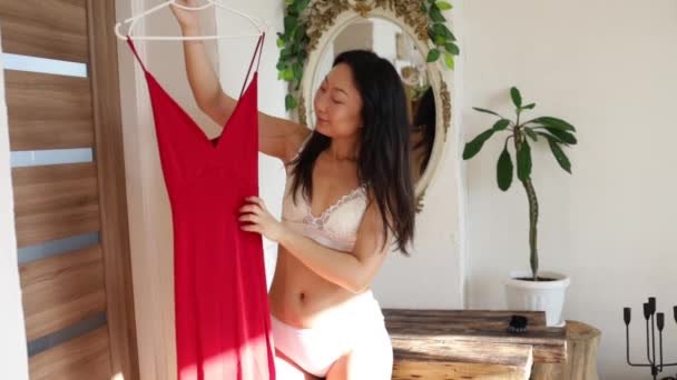 Красивая Молодая Азиатка Проверяет Красное Платье Выглядит Ней Стоя Перед — стоковое видео