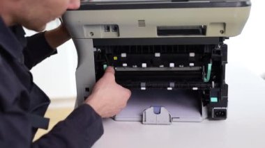 printer repair technician. A male handyman inspects a printer before starting repairs in a client's apartment.
