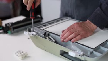 printer repair technician. A male handyman inspects a printer before starting repairs in a client's apartment.