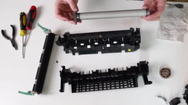 printer repair technician. A male handyman inspects a printer before starting repairs in a client's apartment.