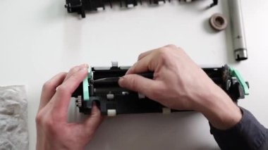 printer repair technician. A male handyman inspects a printer before starting repairs in a client's apartment.
