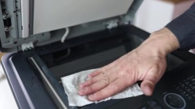 printer repair technician. A male handyman inspects a printer before starting repairs in a client's apartment.