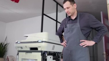 printer repair technician. A male handyman inspects a printer before starting repairs in a client's apartment.