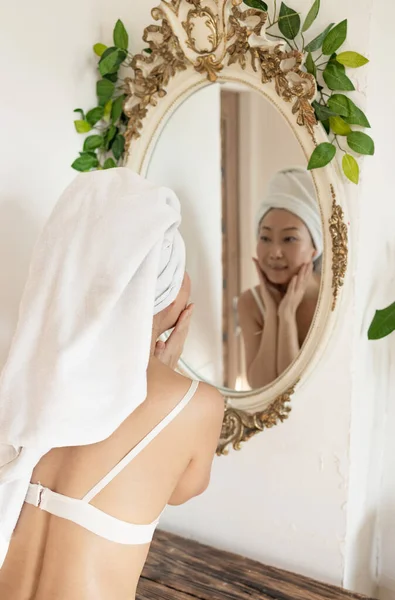 수건을 머리에 아가씨 거울을 습하게 부드러운 피부를 만지고 아침에 공급을 — 스톡 사진
