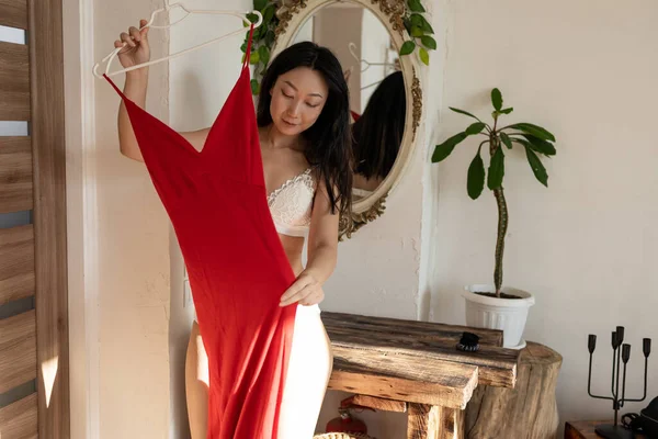 Piękna Młoda Azjatka Sprawdza Jak Niej Wygląda Czerwona Sukienka Stojąca — Zdjęcie stockowe