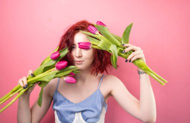 Çiçekli mavi elbiseli güzel bir kız. Pembe arka planda laleler..