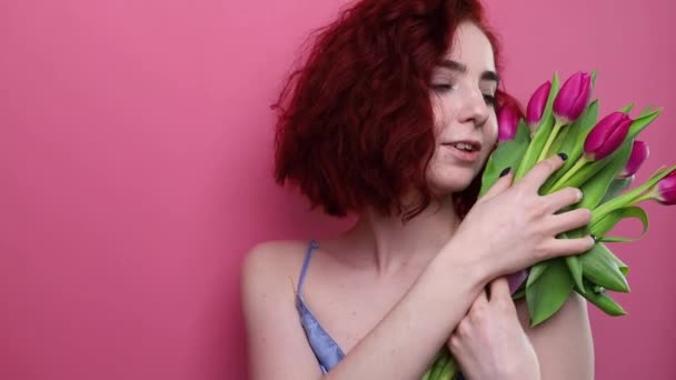 美しいです女の子とともに短い巻き毛と花チューリップで手にピンクの背景 — ストック動画