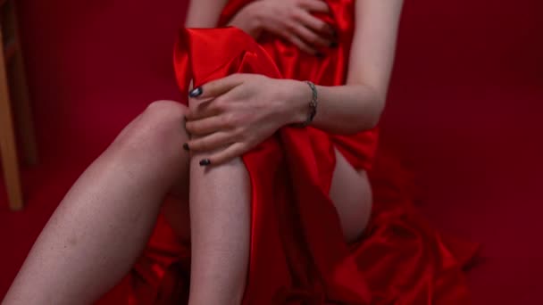 女性は赤い絹の布を赤い背景に滑らかな足の下に投げます 滑らかな足のコンセプト — ストック動画