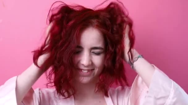 かわいい女の子が遊んで楽しいなびかせ髪を楽しんで回避を欺く ピンクの背景のスタジオの女の子 ヘア製品 美容室 化粧品 ファッション ブティック ピンク — ストック動画